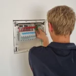 Electrician working on a circuit breaker panel, making electrical connections.