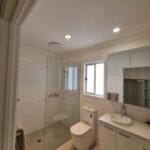 Modern bathroom with a glass shower, vanity, and toilet.