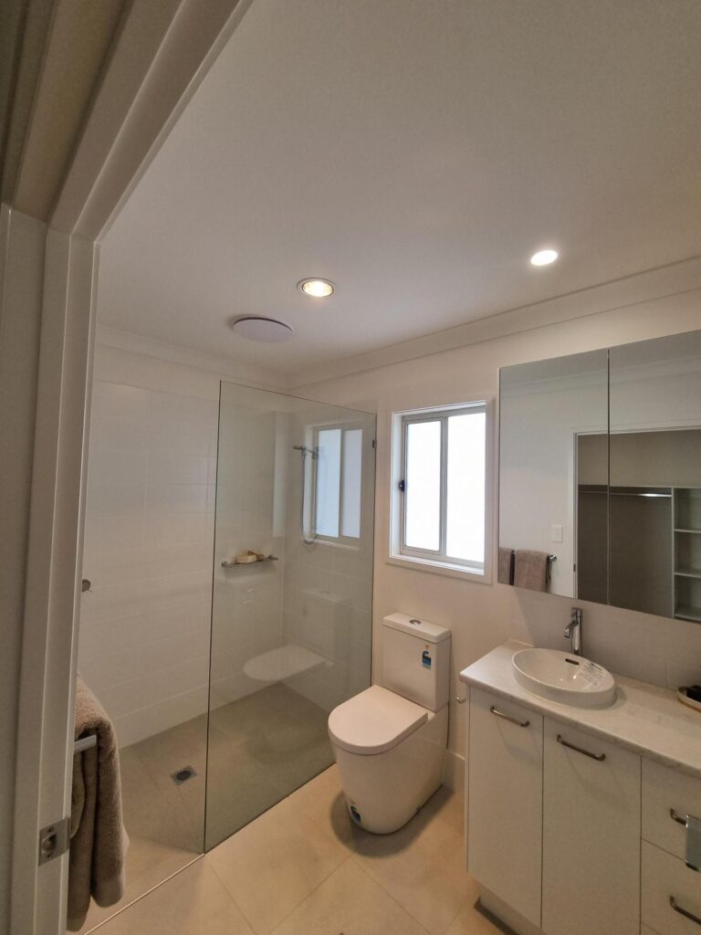 Modern bathroom with a glass shower, vanity, and toilet.