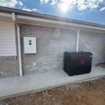 Wall-mounted solar battery and inverter system installed on the exterior of a residential home.