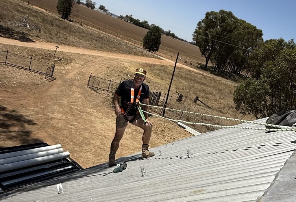 Bright Spark Group securing solar panels on a metal roof with hills in the background. Hassle-free Installations