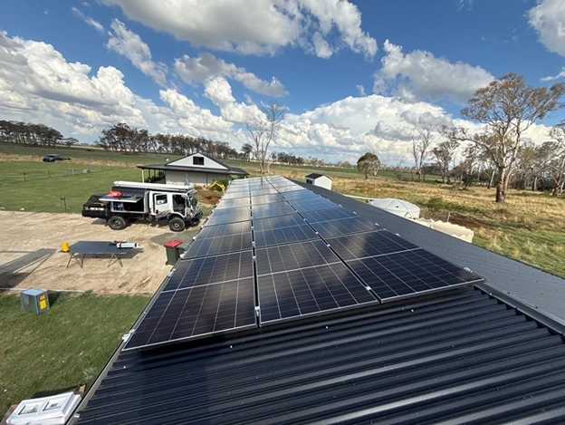 Solar panels installed on a rooftop with a clear sky and rural background.