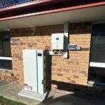 Residential battery storage and inverter system installed on exterior brick wall