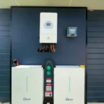 Dual solar battery units with wall-mounted inverter setup on a modern dark-clad building.