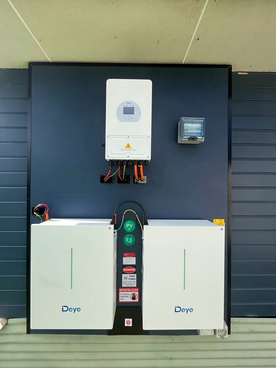 Dual solar battery units with wall-mounted inverter setup on a modern dark-clad building.