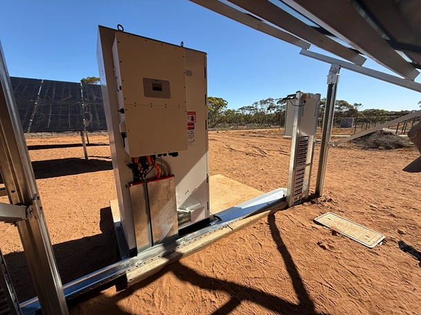 Battery storage system and inverter installed under a solar panel canopy in a remote or rural location.
