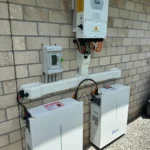 External installation of solar inverter and battery units mounted on a brick wall with visible cabling.