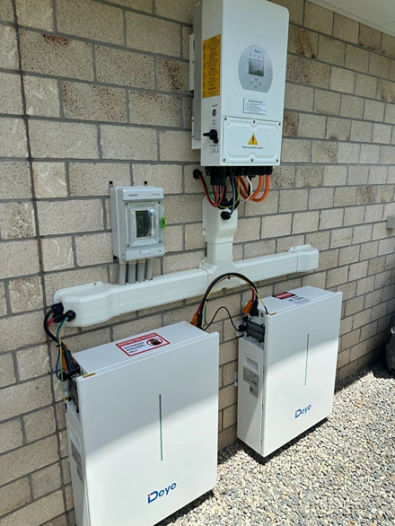 External installation of solar inverter and battery units mounted on a brick wall with visible cabling.