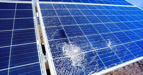Close-up of a damaged solar panel with visible cracks and shattered glass.