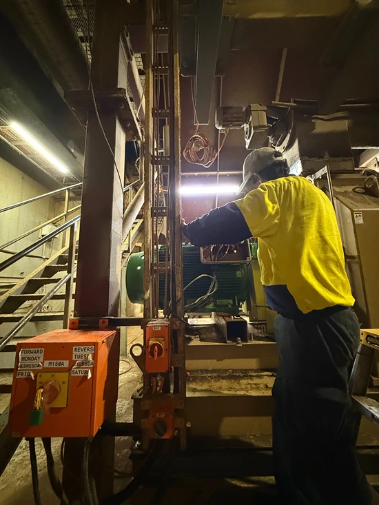 Technician servicing industrial electrical panels in a warehouse, showcasing preventative maintenance in action.