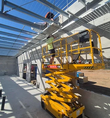 Commercial electrical installation in progress with elevated work platforms under a warehouse roof structure, highlighting safe and scalable infrastructure upgrades.