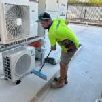 Bright Spark Group Technician Cleaning Around Air-Conditioning System