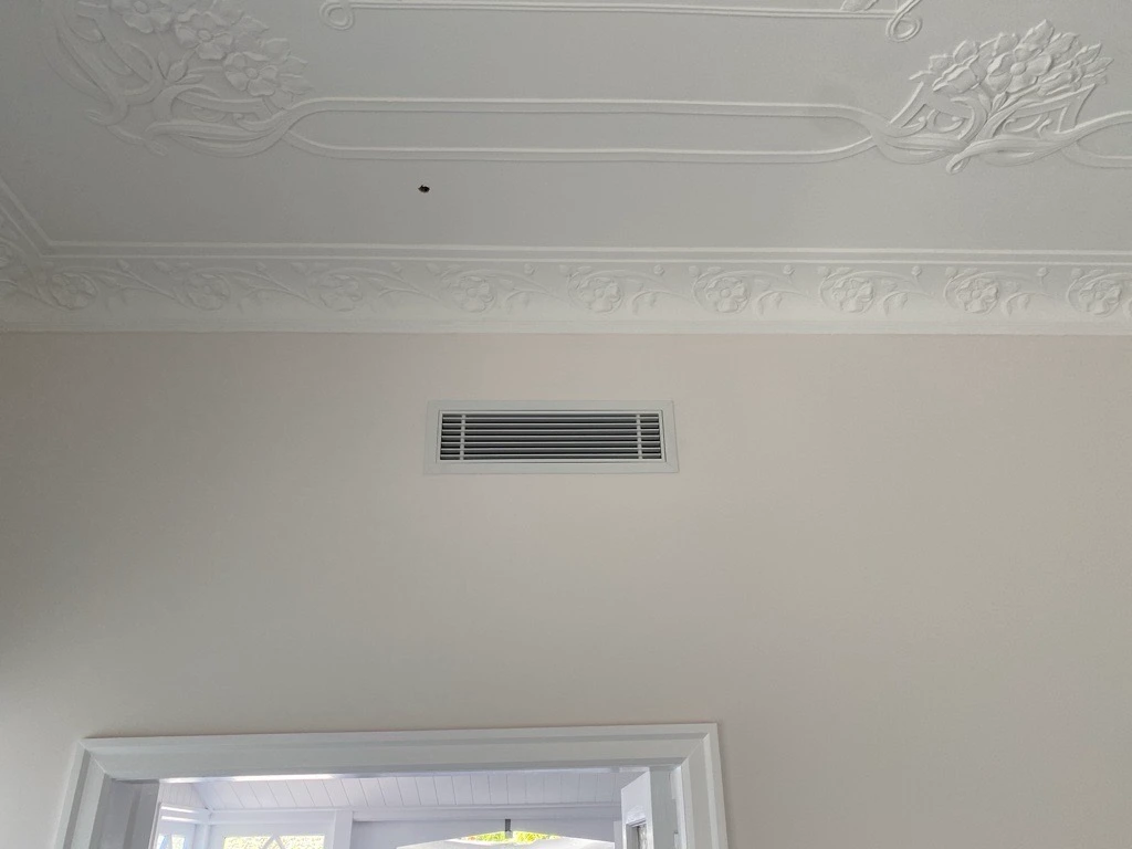 Discreet ducted air conditioning ceiling vent inside a home, providing seamless and silent airflow throughout the living space.