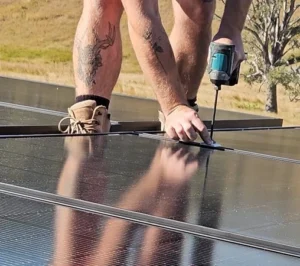 Bright Spark Group solar installers securing rooftop solar panels with a power drill.