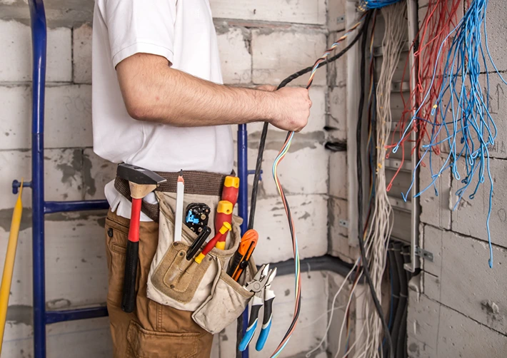 Electrician performing residential electrical upgrades with open switchboard