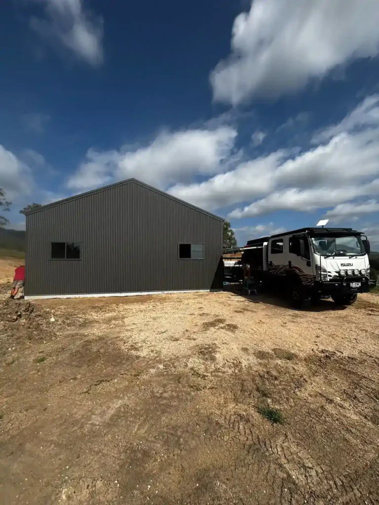 Bright Spark Group off-grid solar shed installation with metal cladding and rural landscape background.