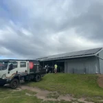 Solar panel installation on rural farm shed roof by Bright Spark Group with service vehicle onsite for renewable energy system setup.