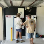 Bright Spark Group technician explaining a solar battery and inverter system to an Ipswich homeowner