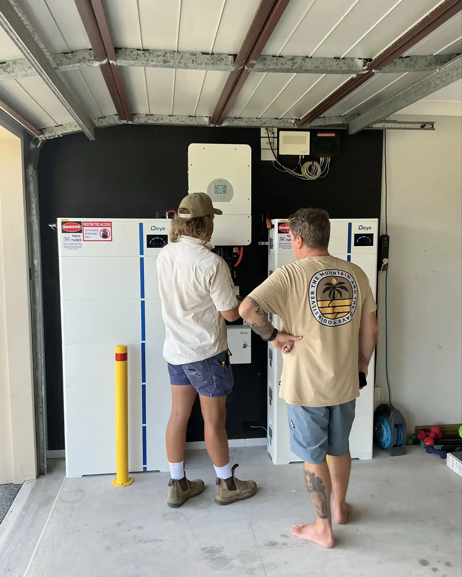 Bright Spark Group technician explaining a solar battery and inverter system to an Ipswich homeowner