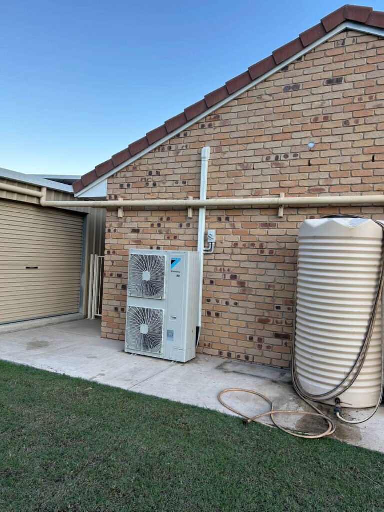 Large Daikin air conditioning outdoor unit installed beside a brick home