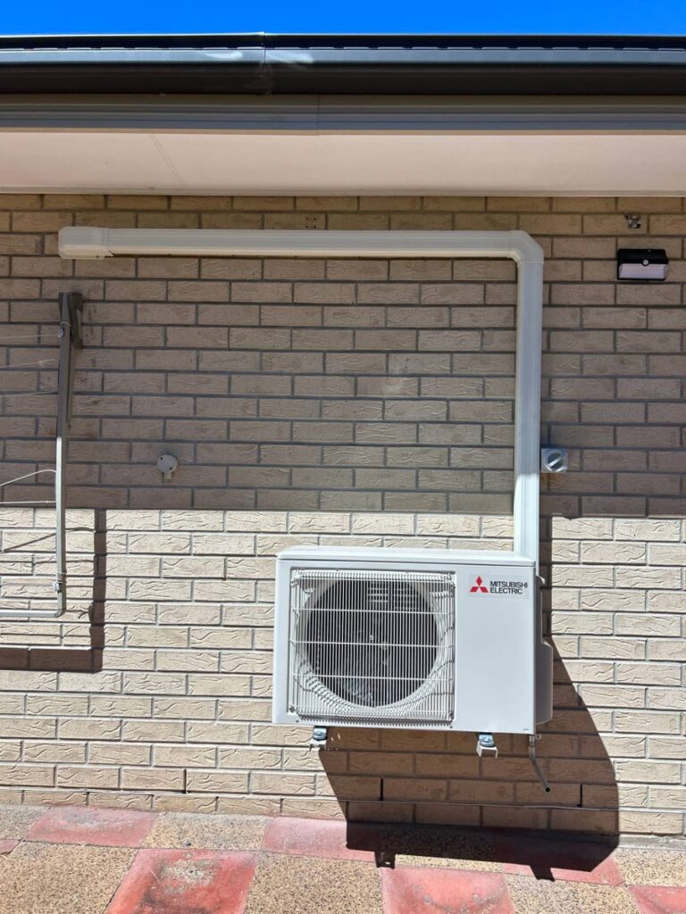 Mitsubishi Electric air conditioning outdoor unit neatly installed on a brick home