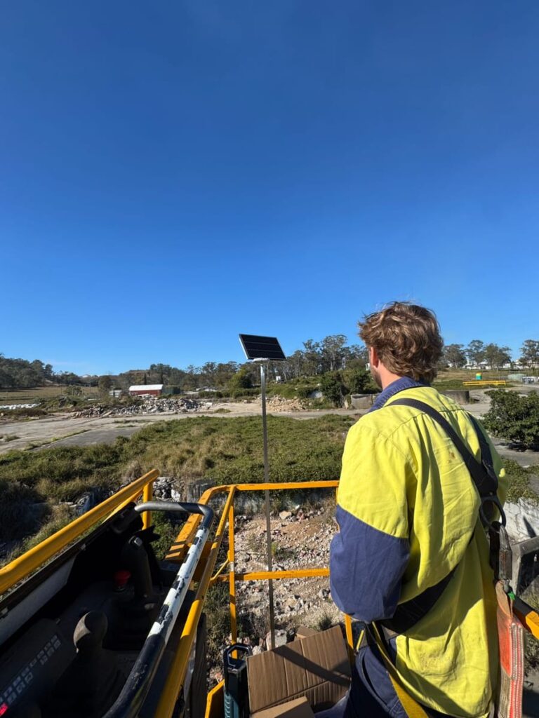 Electrician on an elevated platform beside a solar-powered pole light