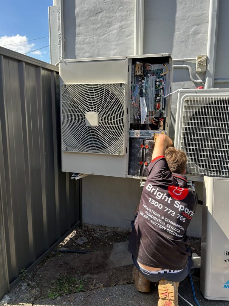 Bright Spark technician servicing a large air conditioning outdoor unit