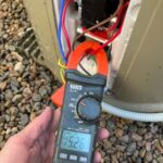 Electrician measuring current at a hot water system with a clamp meter