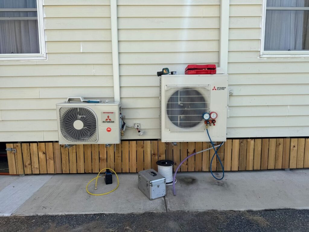 Two air conditioning outdoor units, Mitsubishi Heavy Industries and Mitsubishi Electric, installed on the side of a home