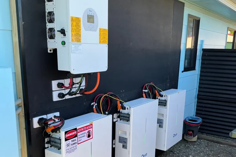 Deye hybrid inverter and battery modules wall-mounted outside a home, installed by Bright Spark Group