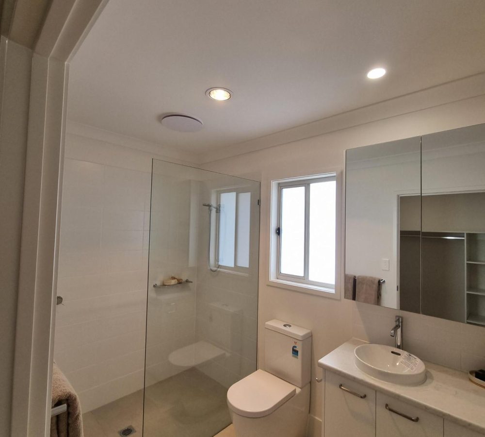 Modern bathroom with a glass shower, vanity, and toilet.
