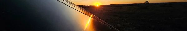 Clean solar panel reflecting a vibrant sunset over a rural landscape.