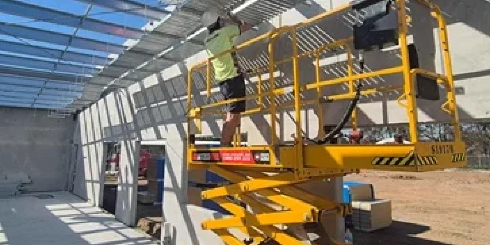 Commercial electrical installation in progress with elevated work platforms under a warehouse roof structure, highlighting safe and scalable infrastructure upgrades.