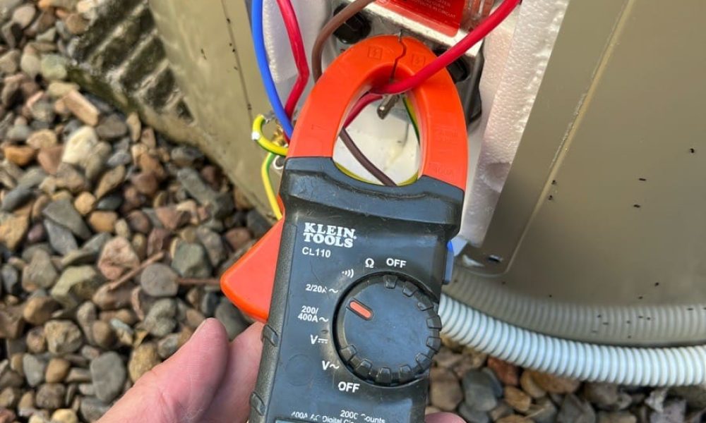 Electrician measuring current at a hot water system with a clamp meter